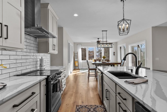 kitchen featuring dishwasher, black range with electric stovetop, hanging light fixtures, wall chimney range hood, and a sink