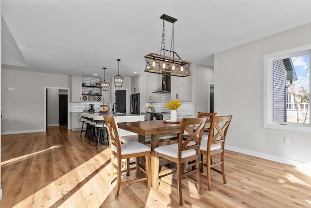 dining room featuring baseboards, recessed lighting, and light wood-style floors