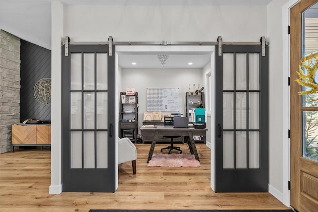 office area featuring a barn door, wood finished floors, and baseboards