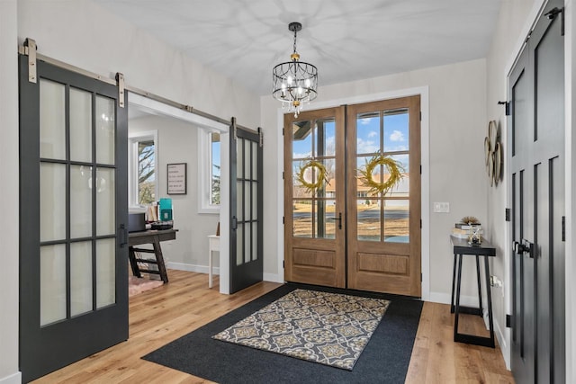 entrance foyer featuring french doors, a barn door, a healthy amount of sunlight, and light wood-style floors