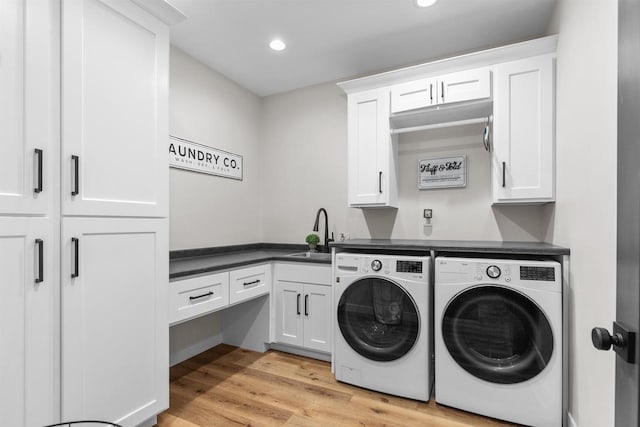 laundry area featuring recessed lighting, a sink, cabinet space, light wood finished floors, and washer and clothes dryer