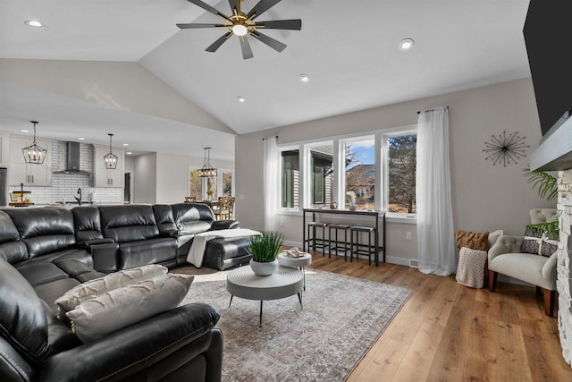 living area with ceiling fan, high vaulted ceiling, recessed lighting, baseboards, and light wood-style floors