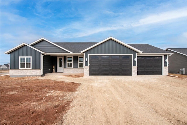 view of front of house with board and batten siding, a garage, roof with shingles, and dirt driveway