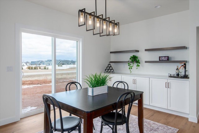 dining space with light wood-type flooring and baseboards