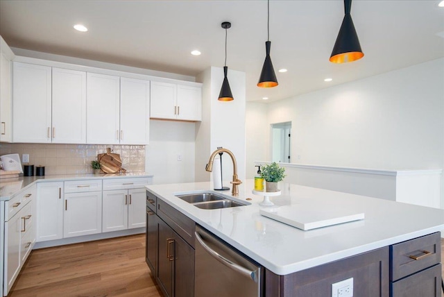 kitchen with a kitchen island with sink, a sink, white cabinets, light wood-type flooring, and dishwasher