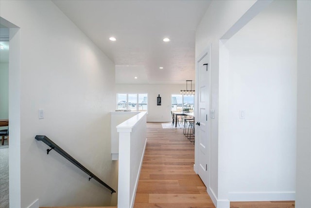 hallway with baseboards, light wood finished floors, an upstairs landing, and recessed lighting