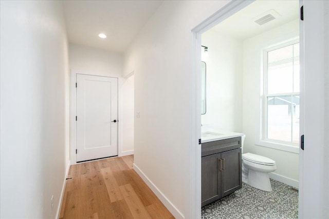 half bathroom featuring baseboards, visible vents, toilet, vanity, and recessed lighting