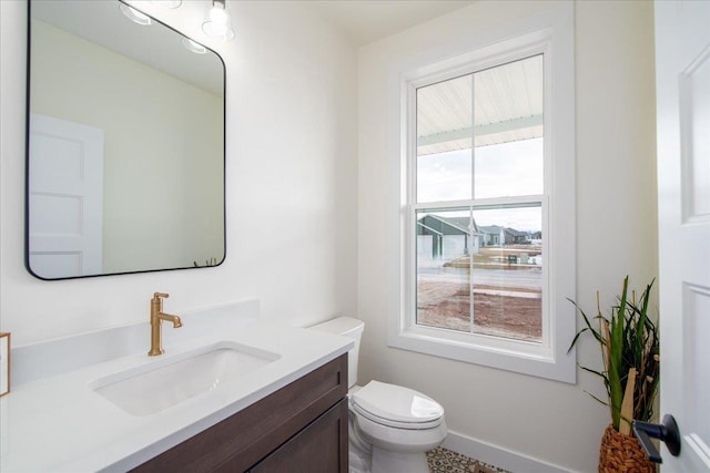 bathroom with vanity, toilet, and baseboards