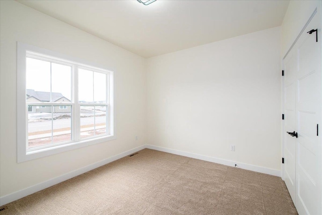 spare room with baseboards and light colored carpet