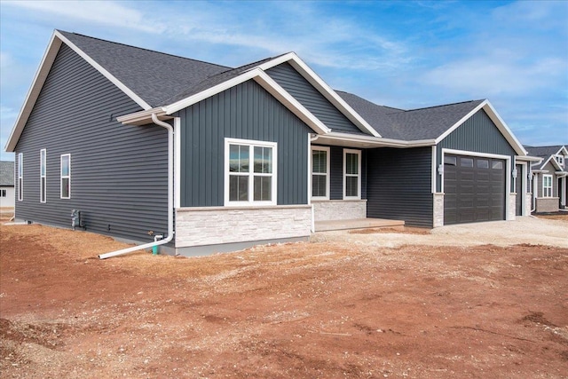 single story home with a garage, stone siding, and a shingled roof