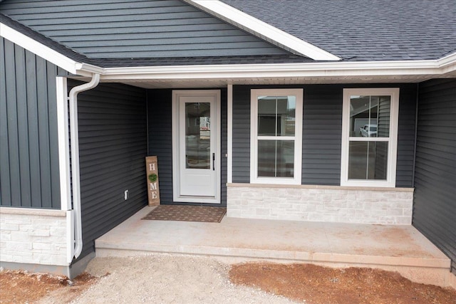 property entrance featuring a shingled roof, stone siding, a porch, and board and batten siding