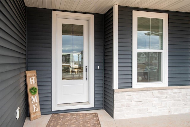 entrance to property with stone siding and a porch