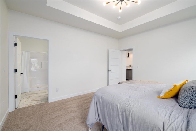 bedroom with a tray ceiling, light carpet, connected bathroom, and baseboards