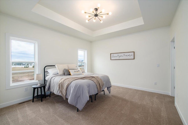 bedroom featuring carpet floors, a raised ceiling, a chandelier, and baseboards