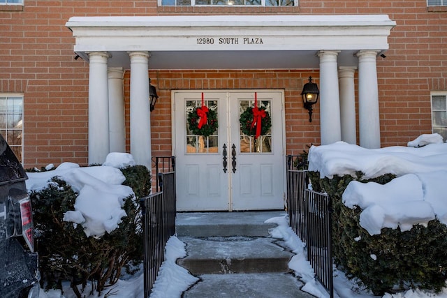 view of exterior entry featuring brick siding and a porch