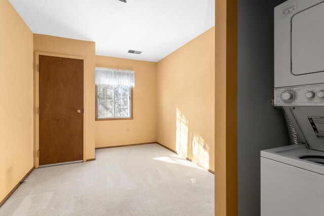 laundry area with carpet, stacked washer / drying machine, visible vents, laundry area, and baseboards