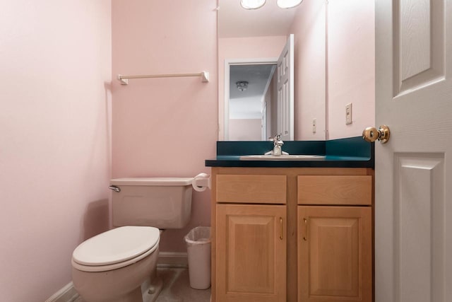 half bathroom with toilet, baseboards, and vanity