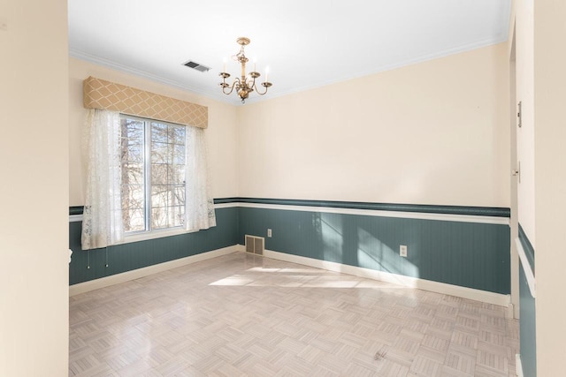 unfurnished room featuring ornamental molding, wainscoting, visible vents, and a notable chandelier