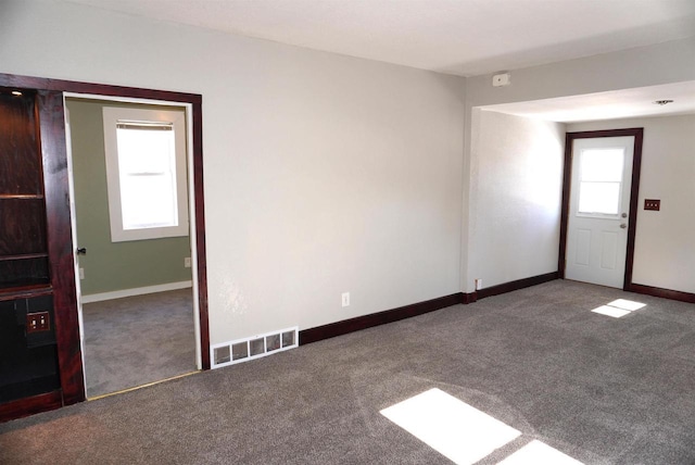 carpeted spare room with visible vents and baseboards