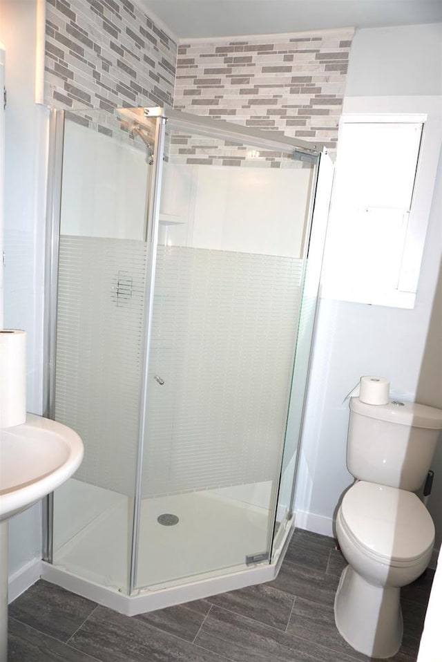 bathroom with a stall shower, toilet, and wood finished floors