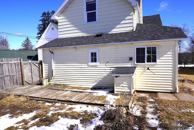 rear view of house with a shingled roof, fence, and a deck