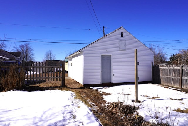 snow covered structure with an outbuilding and fence