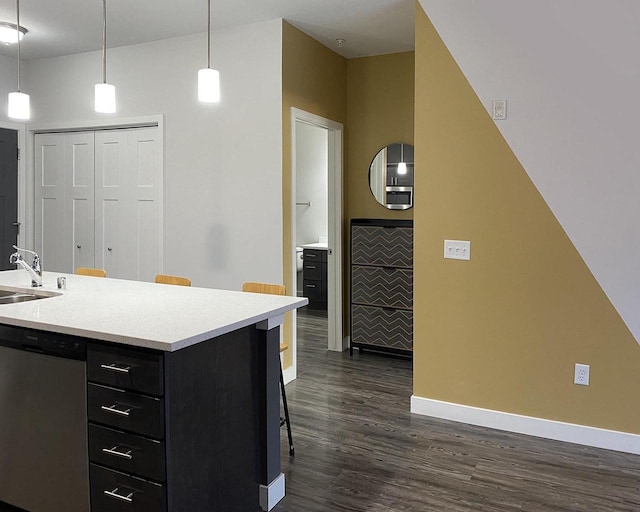 kitchen featuring light countertops, dark cabinetry, dark wood finished floors, and stainless steel dishwasher