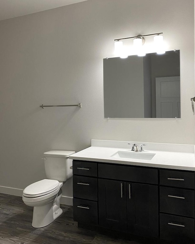 bathroom featuring baseboards, vanity, toilet, and wood finished floors