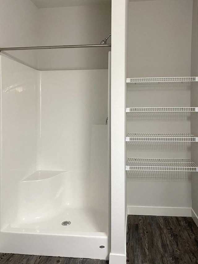 bathroom featuring a stall shower, baseboards, and wood finished floors