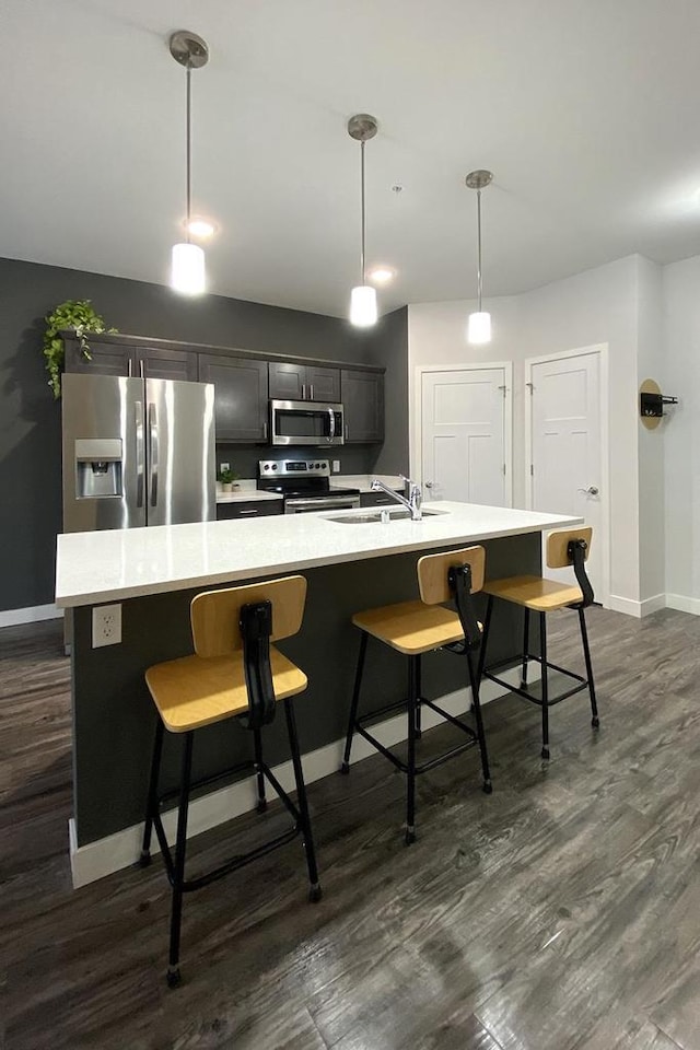 kitchen with baseboards, a breakfast bar area, dark wood-type flooring, stainless steel appliances, and light countertops