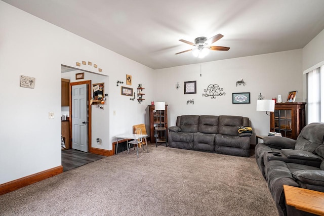 living room with ceiling fan, dark carpet, and baseboards