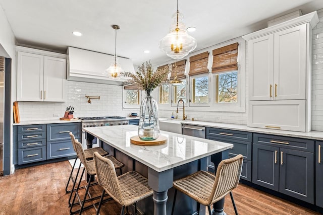 kitchen featuring stainless steel appliances, wood finished floors, white cabinets, and a kitchen breakfast bar