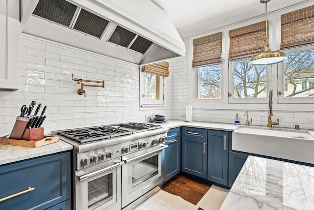 kitchen with extractor fan, a sink, blue cabinetry, double oven range, and tasteful backsplash