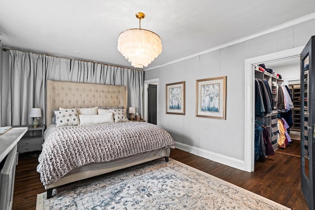 bedroom with a notable chandelier, crown molding, a walk in closet, and wood finished floors