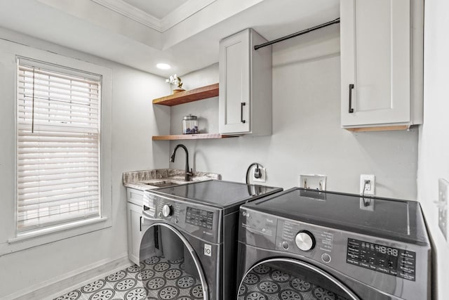 washroom featuring washing machine and clothes dryer, cabinet space, ornamental molding, a sink, and baseboards