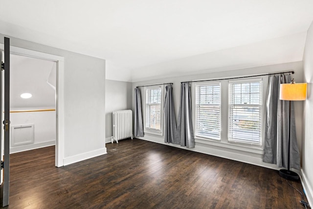 empty room featuring baseboards, wood finished floors, and radiator