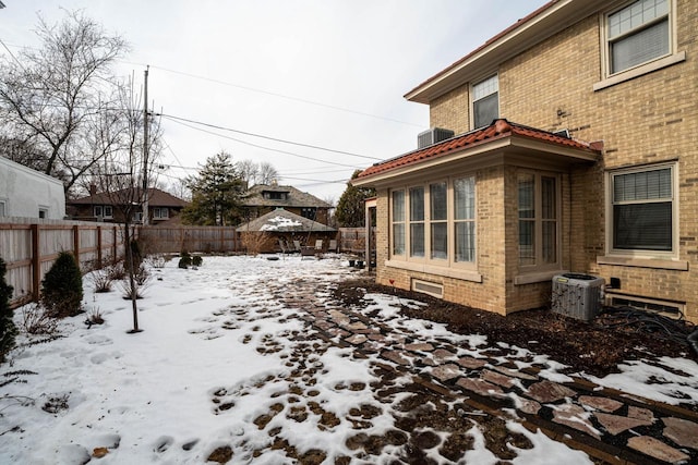 yard covered in snow featuring a fenced backyard and central AC