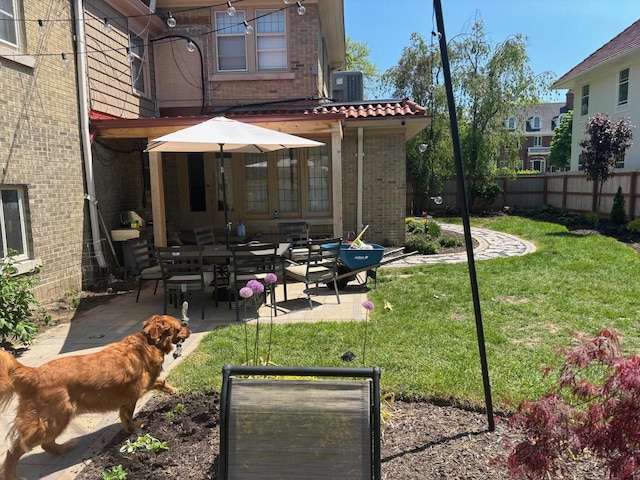 rear view of house featuring a patio, central AC, brick siding, fence, and a lawn