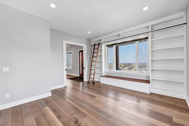 interior space featuring hardwood / wood-style floors, recessed lighting, built in shelves, and baseboards