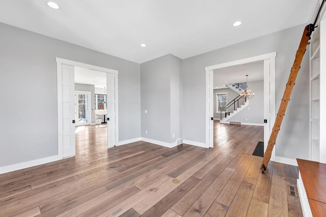 spare room featuring hardwood / wood-style flooring, stairs, baseboards, and recessed lighting