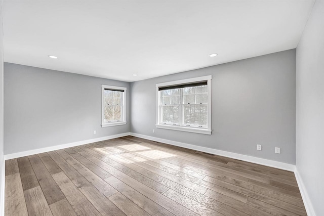 unfurnished room with recessed lighting, hardwood / wood-style flooring, and baseboards