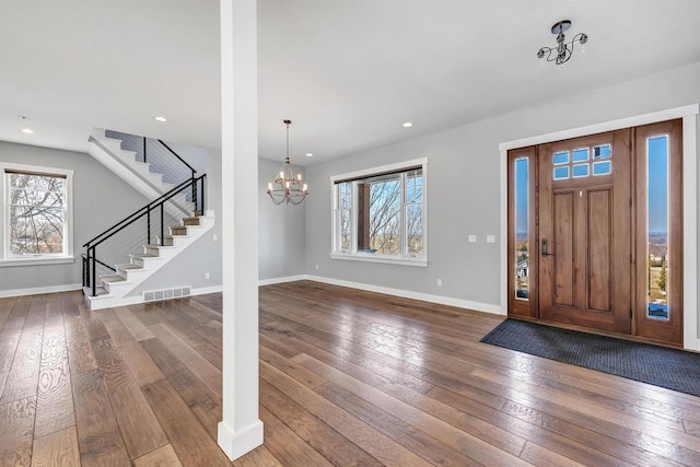 foyer with a healthy amount of sunlight, wood-type flooring, stairs, and visible vents