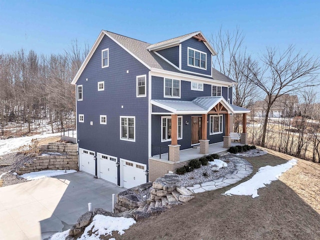 view of front facade featuring a garage, concrete driveway, metal roof, a standing seam roof, and a porch