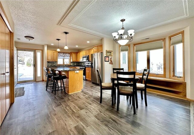 dining space with visible vents, a notable chandelier, a textured ceiling, and wood finished floors