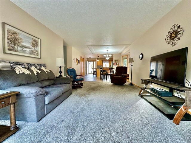 living room with carpet floors, a textured ceiling, and an inviting chandelier