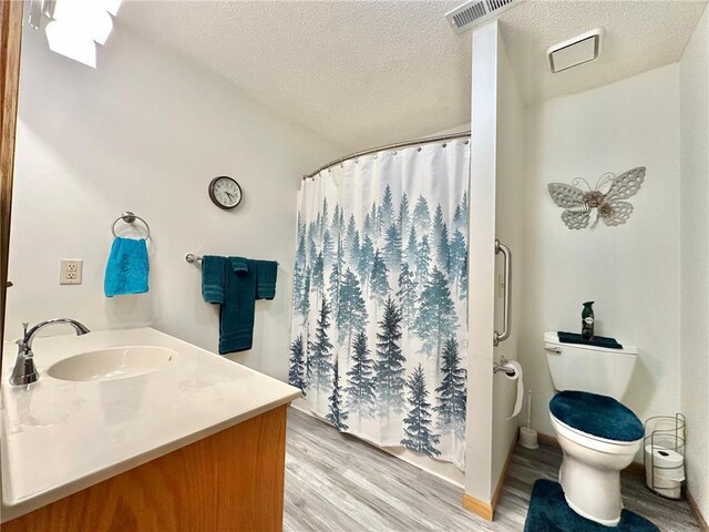 full bathroom with curtained shower, visible vents, toilet, a textured ceiling, and wood finished floors