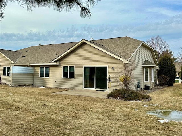 rear view of house featuring a shingled roof, a lawn, and a patio