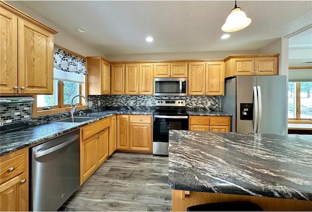 kitchen featuring tasteful backsplash, light wood-style flooring, stainless steel appliances, and a sink