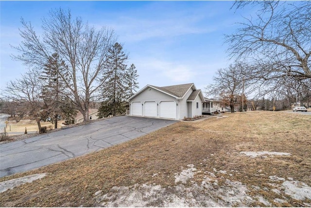 view of side of home with a garage, driveway, and a yard