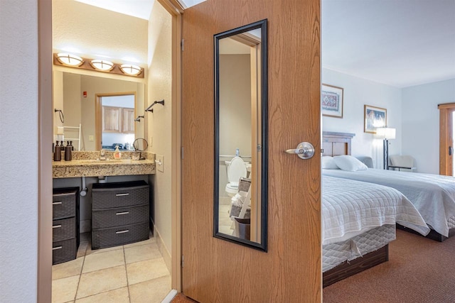 bedroom with a sink, ensuite bath, and light tile patterned floors